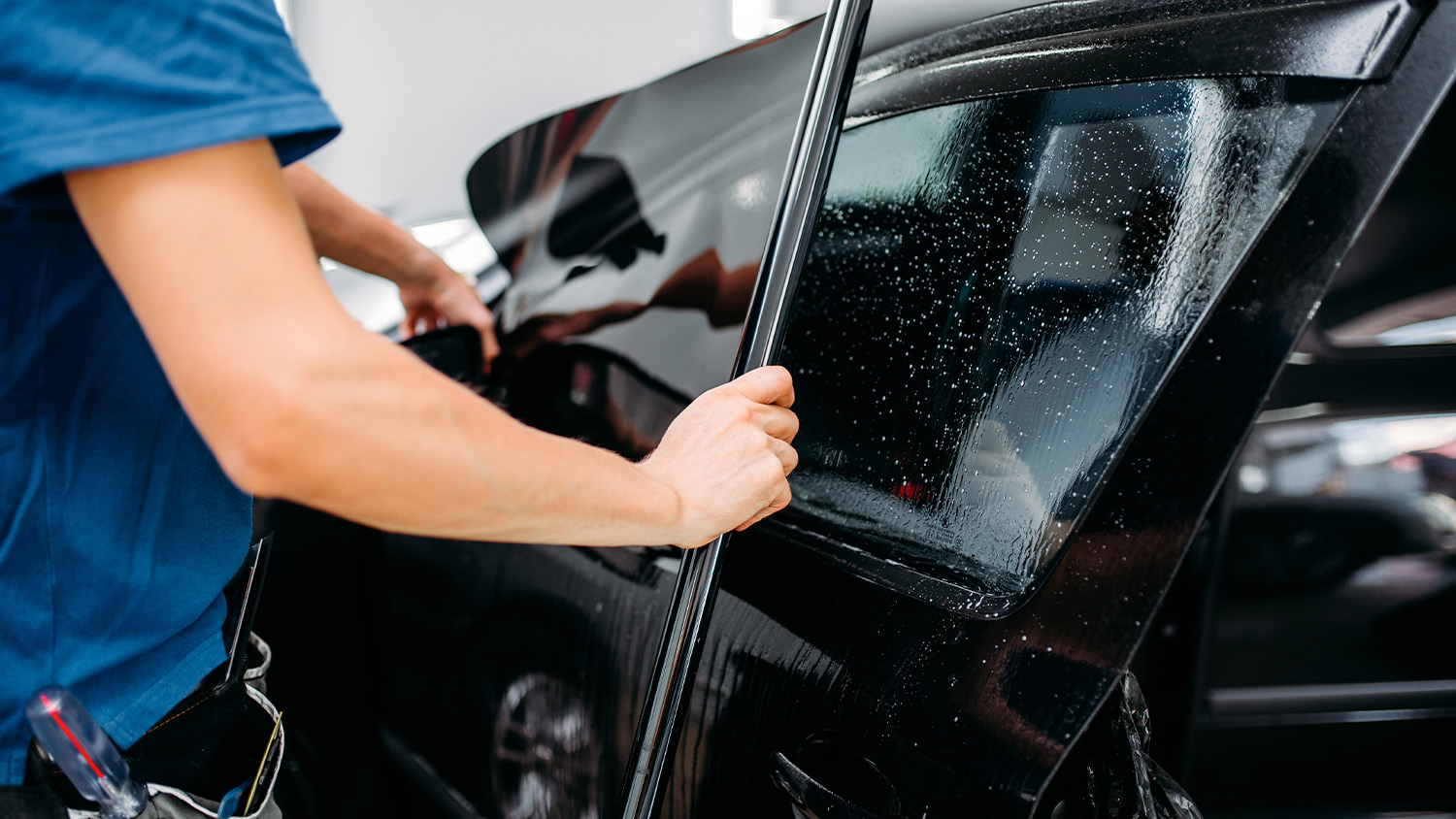 Male tinting a driver side window.