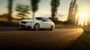 White car driving on a highway with the sun in the background