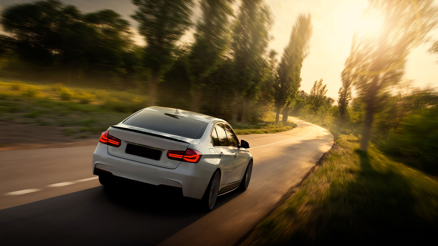 White BMW driving though highway in the sunset