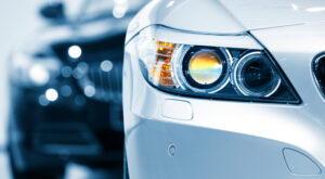 Close up of a white BMW headlight with a black car behind it