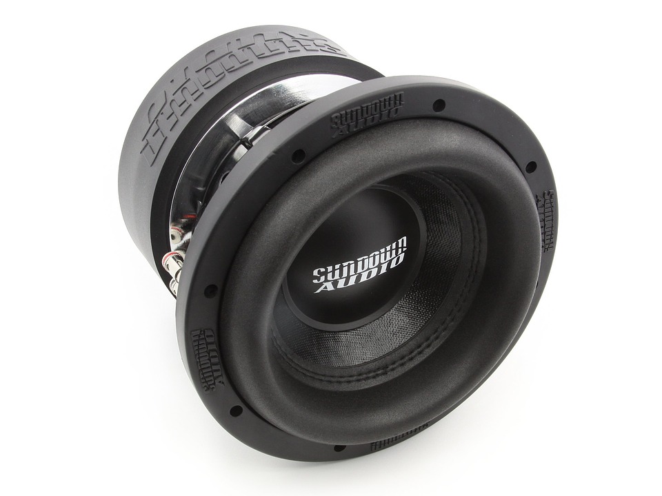 A car subwoofer, outside an enclosure, free of wiring against a white background.