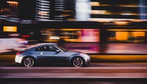 silver sports car driving fast through the city at night