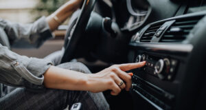 Car dashboard. Radio closeup. Woman sets up radio while driving car