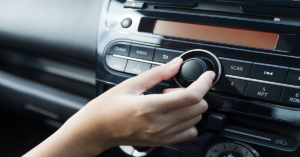 Woman turning button of radio in car